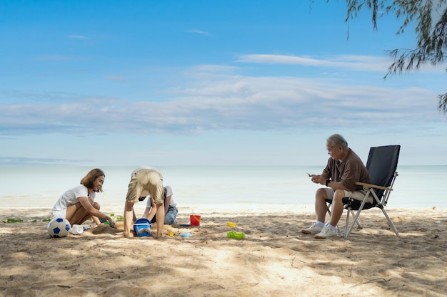 Glückliche asiatische Familie mit Kindern reist und entspannt sich während der Sommerferien am tropischen Strand. Zweisamkeit und Outdoor-Aktivitätslebensstil.