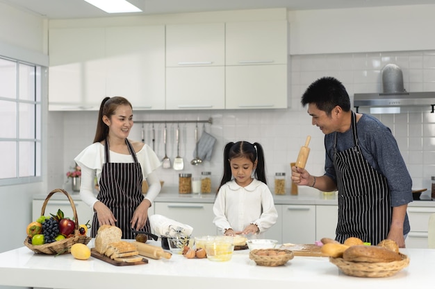 Glückliche asiatische Familie mit Tochter, die Teig zubereitet und Kekse backt Tochter hilft den Eltern, das Backen vorzubereiten Familienkonzept