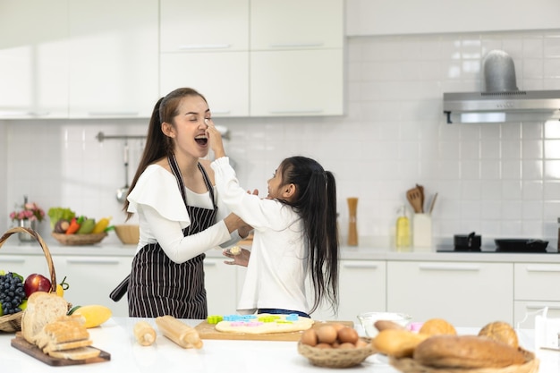 Glückliche asiatische Familie mit Tochter, die Teig zubereitet und Kekse backt Tochter hilft den Eltern, das Backen vorzubereiten Familienkonzept