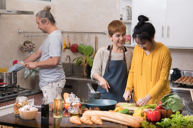 Glückliche asiatische Familie von Mutter, Vater und Tochter, die in der Küche kochen, die zusammen gesundes Essen macht, das Spaß fühlt