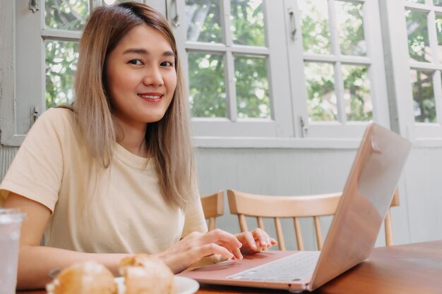 Glückliche asiatische Frau arbeitet online auf einem Computer Tablet im Café Digital Nomad