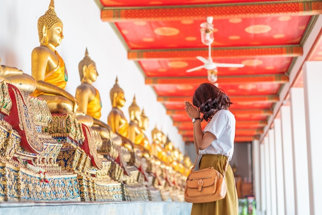 Glückliche asiatische Frau, die mit Buddha betet