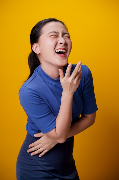 Glückliche asiatische Frau, die zahniges Lächeln zeigt, das über gelb steht.