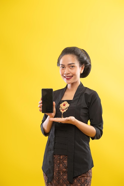 Glückliche asiatische frau mit kebaya, die telefonbildschirm zeigt