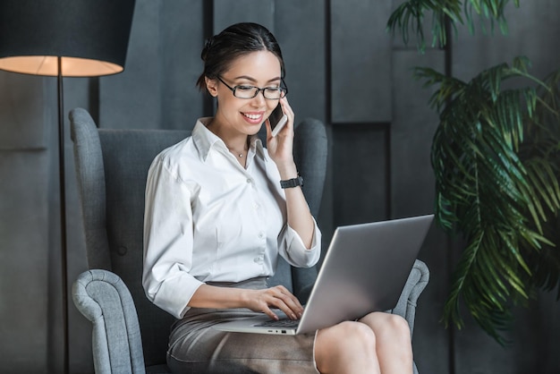 Glückliche asiatische Geschäftsfrau, die Notizbuch für Arbeit verwendet