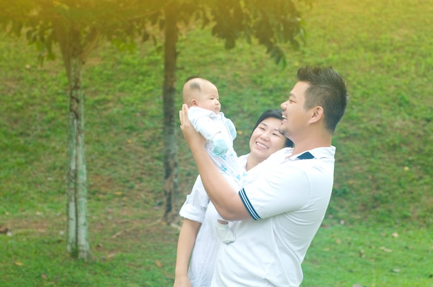 Glückliche asiatische junge Familie, welche die Zeit im Freien an einem Sommertag verbringt