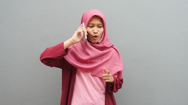 Glückliche asiatische muslimische Frau mit Hijab spricht am Telefon, Frau mit Smartphone, Kommunikationskonzept
