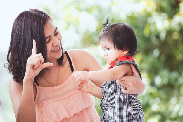 Glückliche asiatische Mutter und nettes kleines Baby, die zusammen mit Spaß und Liebe spielt