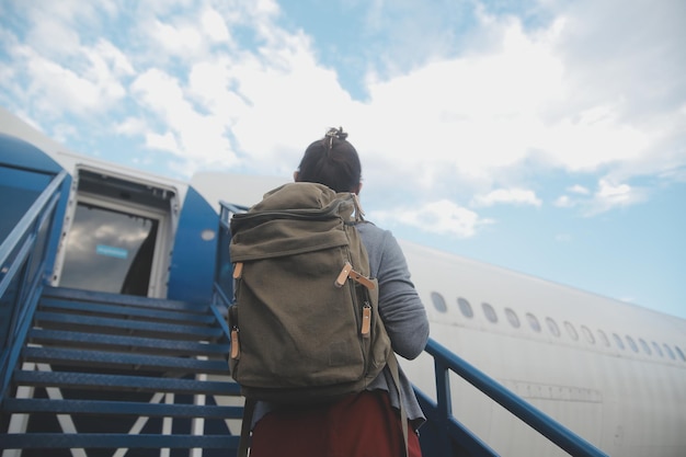 Glückliche, attraktive asiatische Reisende mit Rucksack im modernen Flughafenterminal Kopierraum Touristenreise-Trip-Konzept