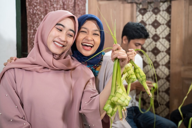 Glückliche aufgeregte Gruppe von Freunden und Familie, die zusammen Ketupat für Eid Fitr Mubarak oder Idul Fitri Lebaran Tradition machen