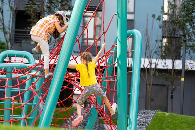 Glückliche aufgeregte Kinder, die Spaß zusammen auf Spielplatz haben