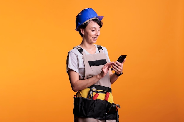 Glückliche Auftragnehmerin surft mit der Handy-App im Internet und liest Social-Media-Texte im Hintergrund. Fröhlicher Profi-Baumeister nutzt Smartphone-App oder Netzwerk im Studio.