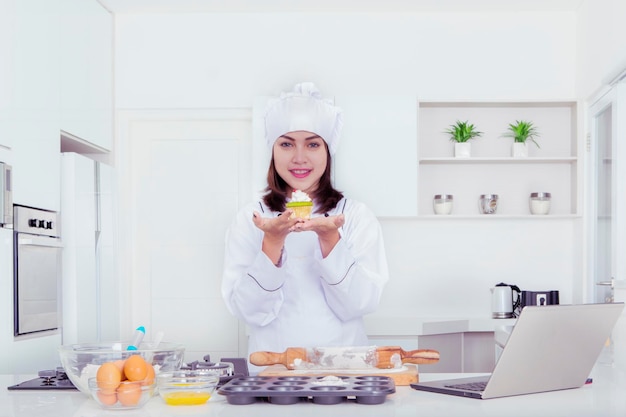 Glückliche Bäckerin, die einen leckeren Cupcake zeigt