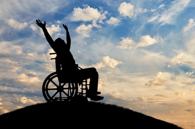 Glückliche behinderte Person im Rollstuhl mit erhobenen Armen. Das Konzept von glücklichen Menschen mit Behinderungen