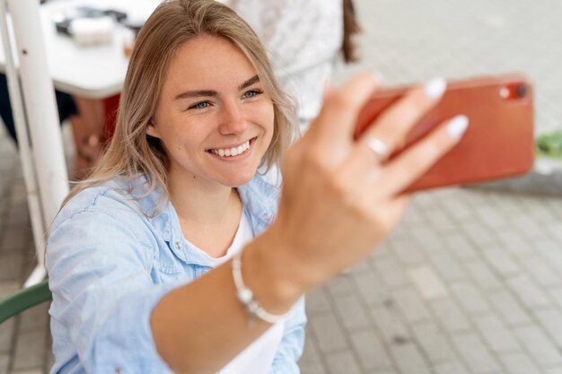 Glückliche blonde Frau macht ein Selfie oder macht einen Videoanruf