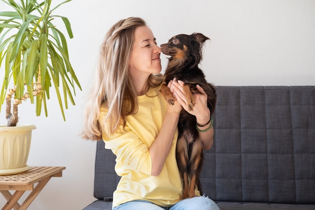 Glückliche blonde Frau mit lustigem braunem russischem Spielzeugterrier. Spaß haben. schnüffeln. Haustierpflegekonzept.