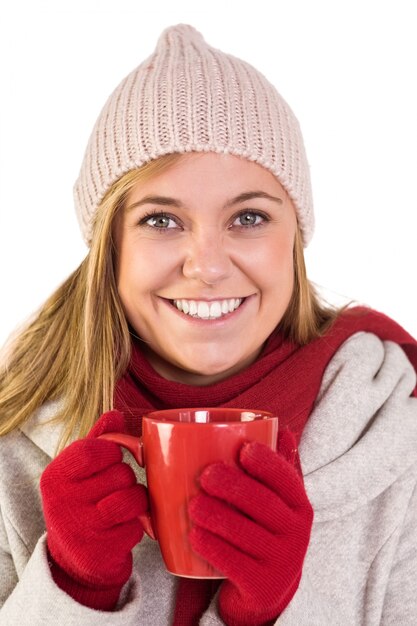 Glückliche Blondine in der Winterkleidung, die Becher hält