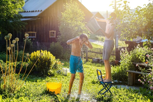 Foto glückliche brüder spritzen wasser im hinterhof