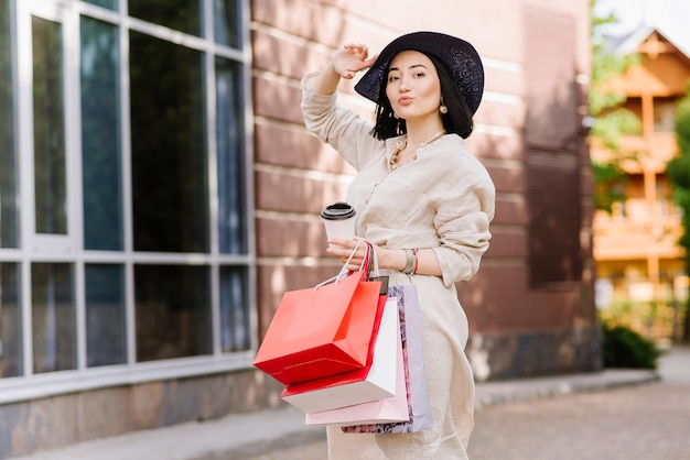 Glückliche Brunettefrau, die draußen Einkaufstaschen hält. Shopoholic-Frau, die mit den Einkäufen zufrieden ist