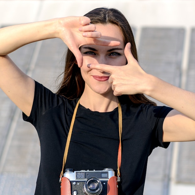 Glückliche Brunettefrau, die Foto mit Retro- Kamera auf Stadtstraße macht