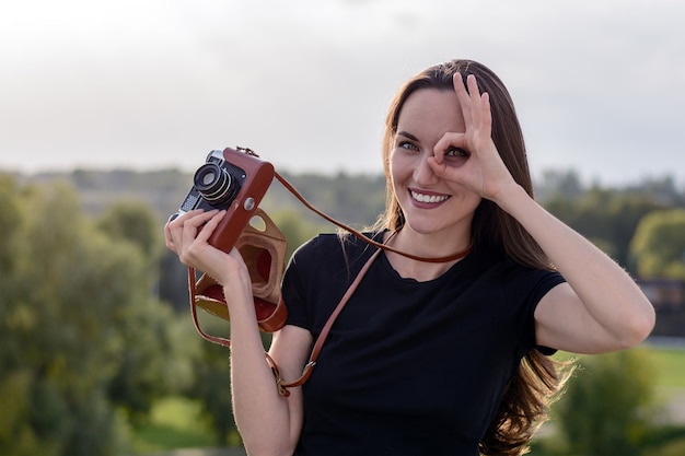 Glückliche Brunettefrau, die Foto mit Retro- Kamera auf Stadtstraße macht