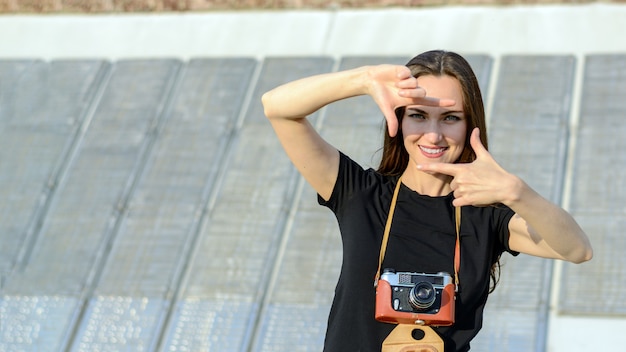 Glückliche Brunettefrau, die Foto mit Retro- Kamera auf Stadtstraße macht