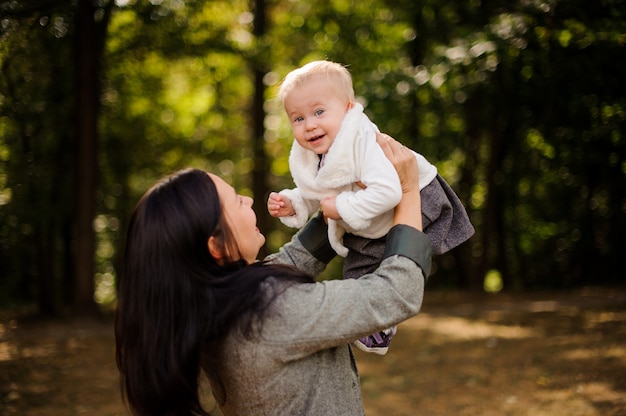 Glückliche Brunettemutter, die mit einer lächelnden Babytochter spielt