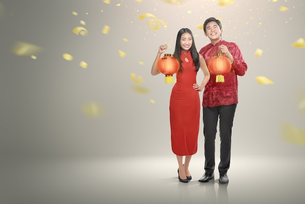 Glückliche chinesische Paare in der cheongsam Kleidung, die rote Laternen hält