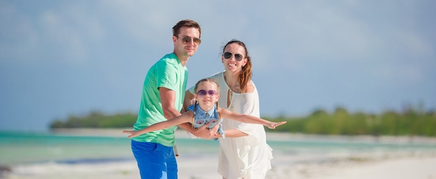 Glückliche dreiköpfige Familie, die zusammen Spaß am Strand hat