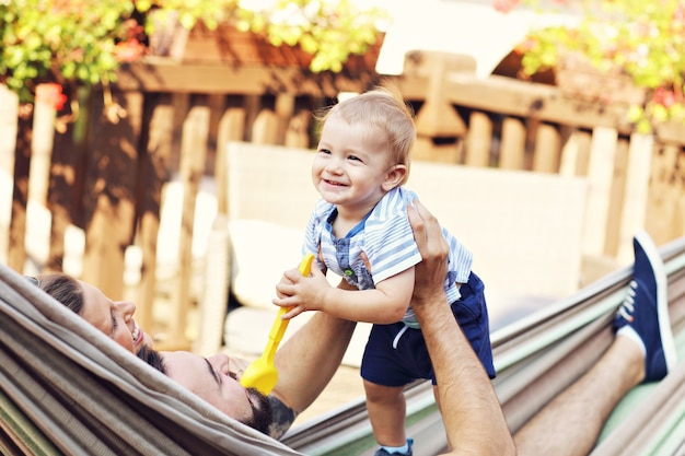 Glückliche Eltern, die draußen mit ihrem Baby in der Hängematte spielen