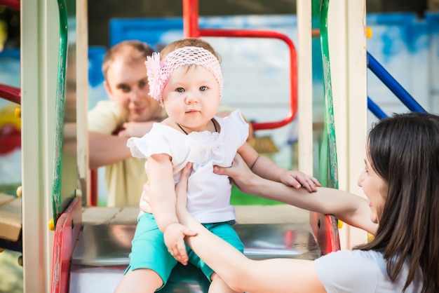 Glückliche Eltern gehen und spielen mit ihrer kleinen Tochter