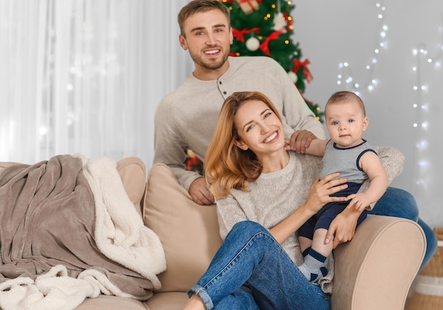 Glückliche Eltern mit Baby im dekorierten Zimmer für Weihnachten