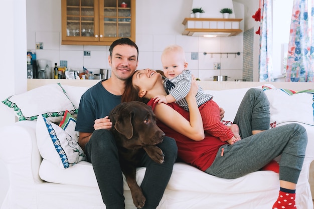 Foto glückliche eltern mit baby und hund auf der couch zu hause lifestyle-familienkonzept