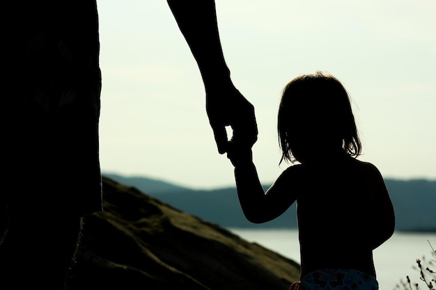 Foto glückliche eltern mit kind in der natur am meer silhouette