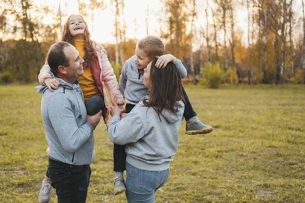 Glückliche Eltern mit Kindern, die im Park spielen, lieben Ihre vierköpfige Familie