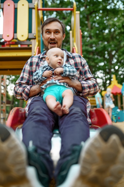 Glückliche Eltern spielen mit kleinem Baby auf Spielplatz im Sommerpark