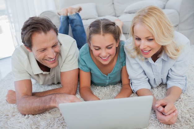 Glückliche Eltern und Tochter, die einen Laptop verwenden