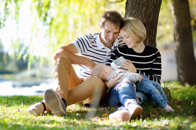 Glückliche Elternschaft: junge Eltern mit ihrem süßen Baby im sonnigen Park
