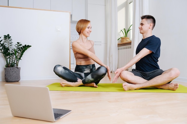 Glückliche erwachsene Geschwister, die zu Hause Yoga machen. Verdrehen in einer einfachen Pose