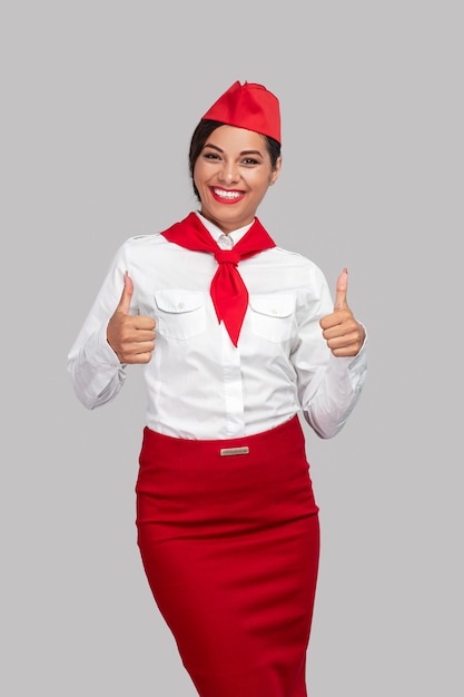 Glückliche erwachsene Stewardess, die Daumensignal zeigt