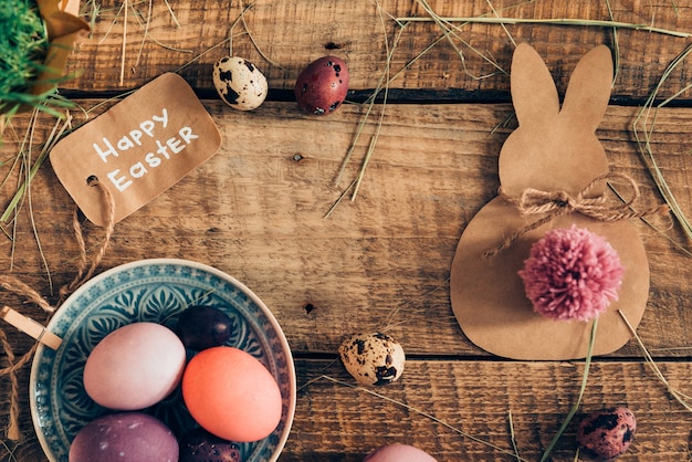 Glückliche Ester! Draufsicht auf farbige Ostereier und Osterdekorationen, die auf rustikalem Holztisch liegen