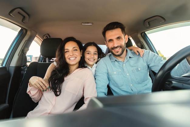 Glückliche europäische Familie mit Kind Mädchen sitzt im Auto und lächelt in die Kamera und genießt die Fahrt in