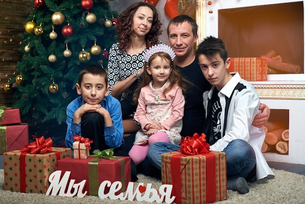 Glückliche Familie am Baum am Kamin. Mama, Papa und drei Kinder im Winterurlaub. Heiligabend und Silvester.