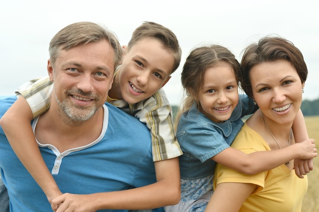 Glückliche Familie am grünen blühenden Feld des Sommers