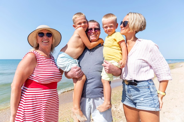 Glückliche Familie am Meer an einem sonnigen Tag Lachende Großeltern Mutter und kleine Kinder umarmen und lächeln Reisen und aktiver Lebensstil Liebe und Zärtlichkeit