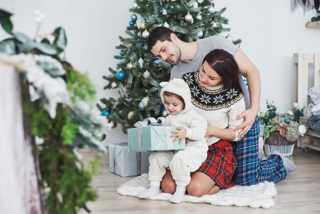 Glückliche Familie am Weihnachten in den Morgenöffnungsgeschenken zusammen nahe dem Tannenbaum.