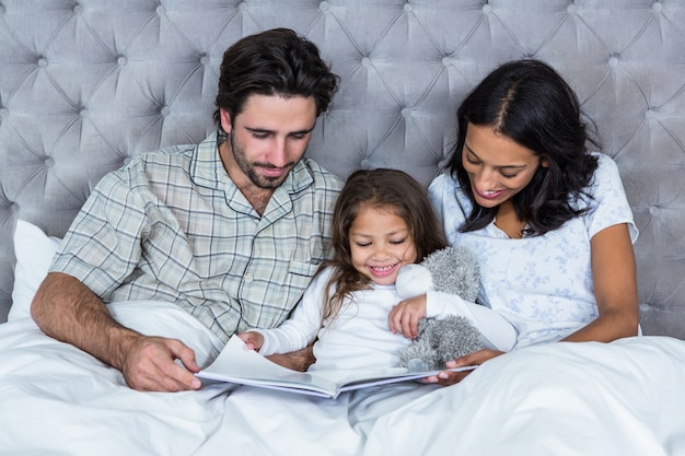 Glückliche Familie auf Bettlesebuch