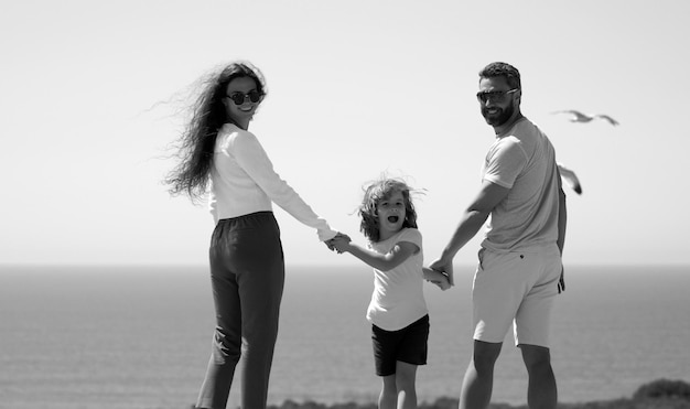 Glückliche Familie auf den Strandleuten, die Spaß im Sommerurlaub haben, Vater, Mutter und Kind auf blauem Meer c