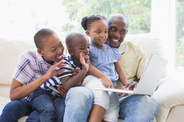 Glückliche Familie auf der Couch, die mit Laptop plaudert
