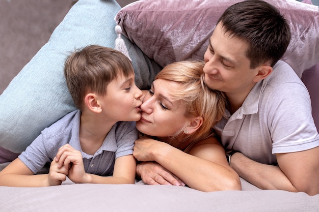 Glückliche Familie auf einem Bett mit weichen Kissen zu Hause
